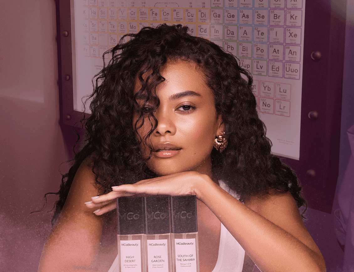 Girl with hand on 3 fragrance bottles and chart behind her